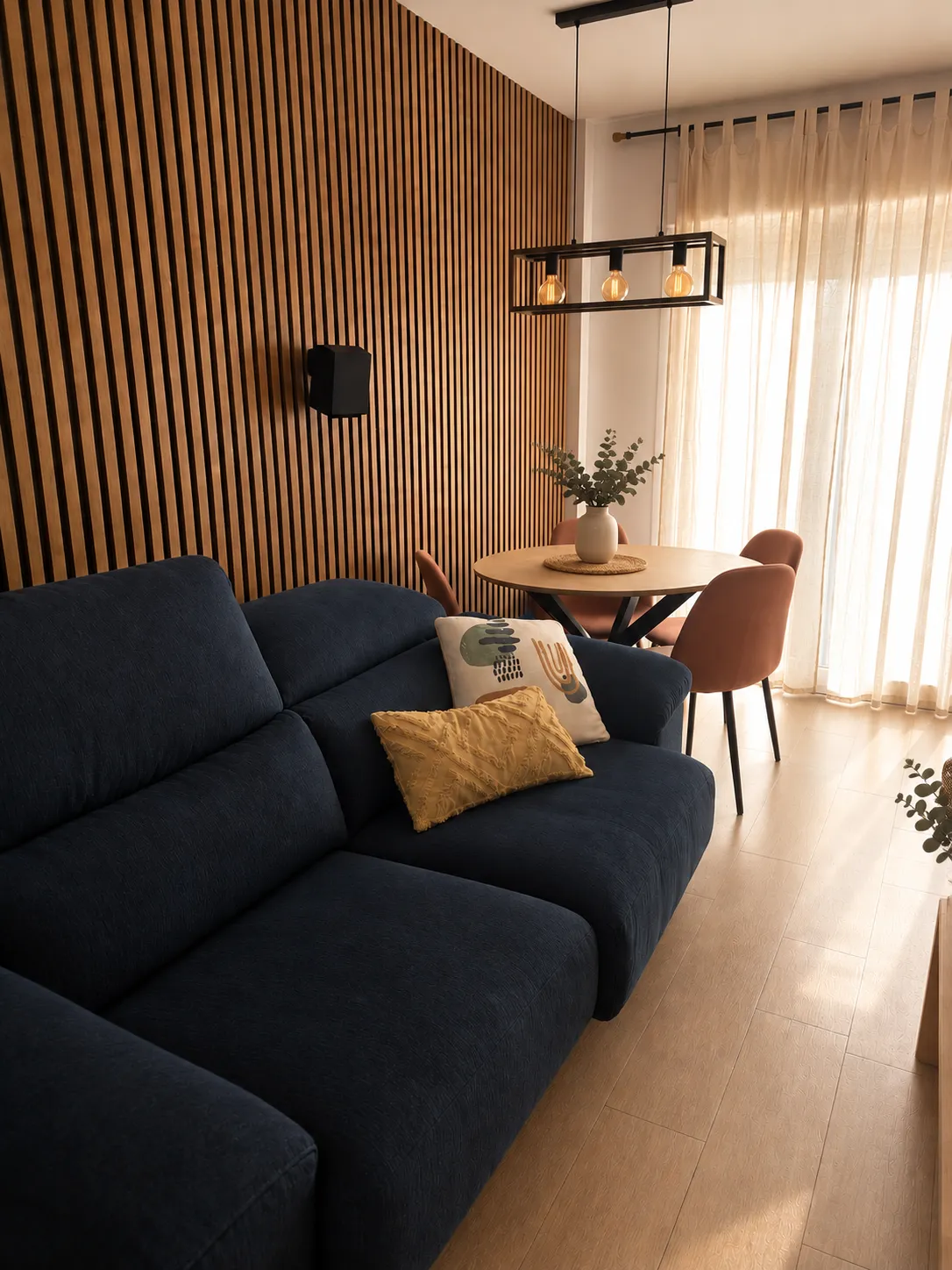 Casa Garpe living-dining room: midnight blue sofa against the wooden slat wall, dining area with terracotta chairs and linen curtains